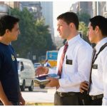 Two male Mormon missionaries talking with a young man on the street