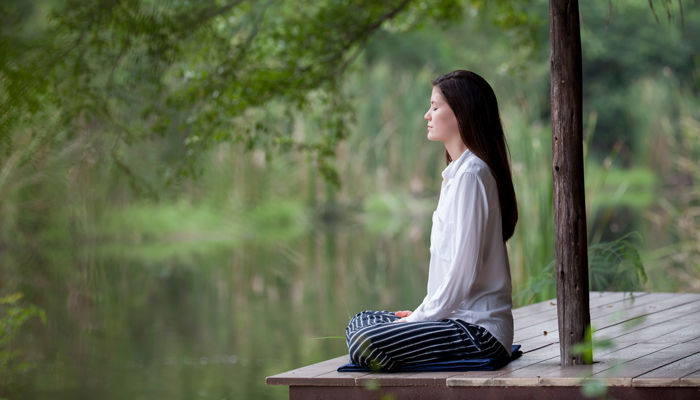 Woman meditates on dock
