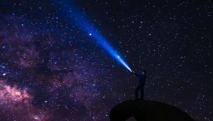 Man with flashlight looking at stars