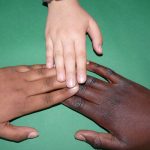 three hands of various races touching