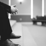 B&W legs of man praying alone in church