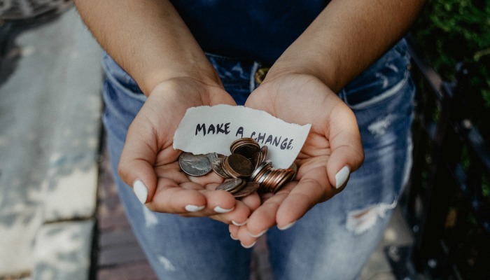 Hands holding coins and paper saying "Make a change"