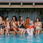 multiple women sitting by pool wearing modest swimsuits