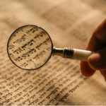 Magnifying glass over Hebrew text.
