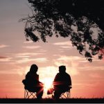 couple sitting together under tree talking
