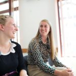 two sister missionaries laughing together sitting down